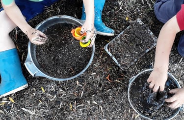 two boys playing with dirt in a garden