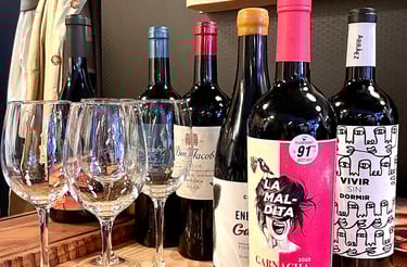 Four wine glasses lined up in front of four bottles of red Spanish wine