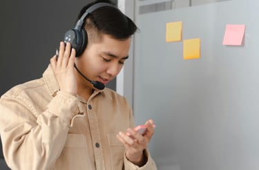 A young man holding a paper in his hand a has headphone on his head.
