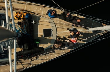 A group of people standing on a sailing boat in the lyngen alps looking to t he sky