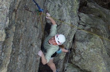 Kletterkursteilnehmerin ist glücklich über geschaffte Route bei einem Outdoor - Kletterkurs.