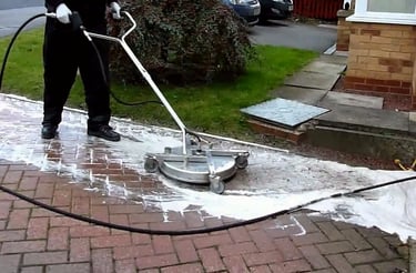 A man using a surface cleaner to clean a brick paver path