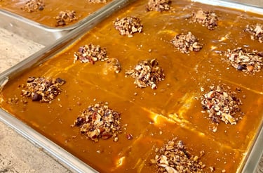 Two baking trays filled with homemade pumpkin bars topped with caramel glaze and chopped pecans.