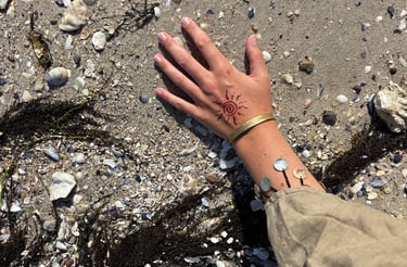 a person's hand with a wrist tattoo on it on earth with shells tribal pattern art handmade