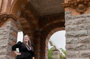 A businesswoman standing in the opening of a stone gazebo-like structure