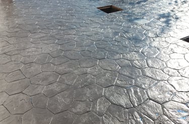 Pavimento de hormigón impreso en color negro con diseño de piedra irregular, ideal para superficies exteriores elegantes y du