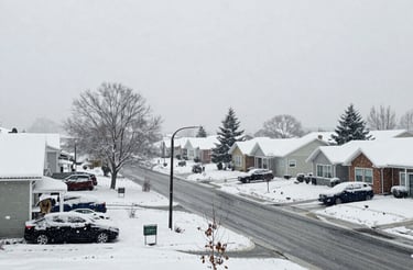 A friendly person holding a clipboard standing next to a snow-covered driveway.