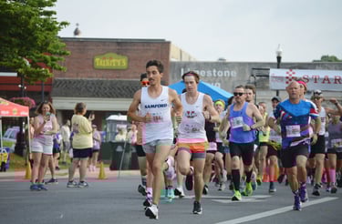 A photo of runners sprinting away from the starting line of the Athens Alabama Chick Fil A 10K start