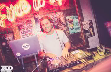 DOXIS djing in front of a neon sign