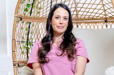 spa business coach sitting in her spa reception area chair in pink scrubs