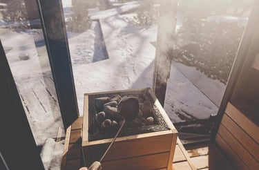 Pouring water on hot sauna stones inside a cedar Outdoor sauna Ontario with winter sunlight