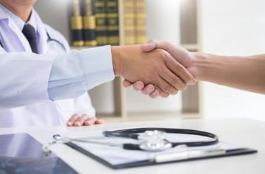 Profissional da saúde em consultório apertando a mão do paciente