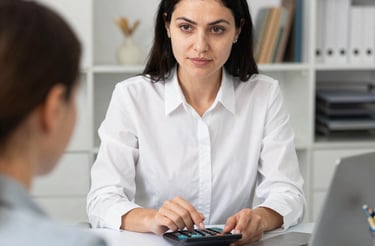 A friendly person typing on a laptop with a notepad and pen nearby.