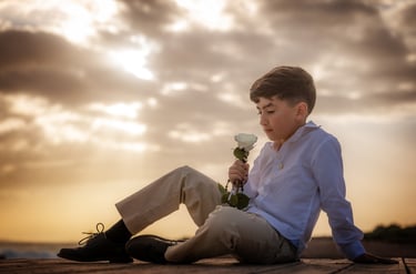 a boy sitting on a wooden deck with a flower