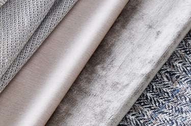 A collection of luxury upholstery fabric swatches in neutral grey, beige, velvet, and patterned textures.