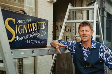 a man standing next to a sign that says,'sign writer '