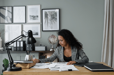 a woman sitting at a desk with a laptop and papers
