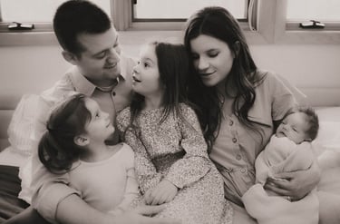 Black and white photo of the full family on the master bed during a Grand Rapids newborn session.