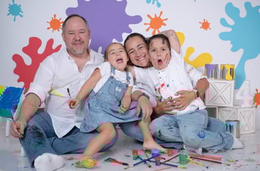 a family posing for a photo in front of a wall with paint splatters
