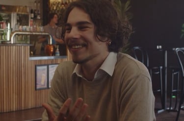 a man sitting at a table with a glass of wine