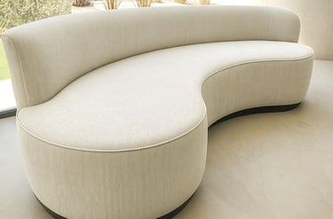 Curved light-gray upholstered sofa with textured fabric and black base in modern room with natural light — by Solo Home Decor