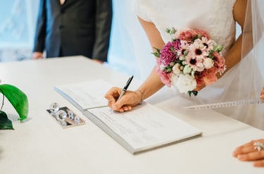 Bride signing the wedding register with bouquet—enquire to book your Glasgow wedding videographer.