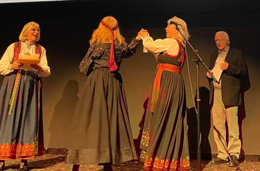 a woman in bunad singing, a man singing and two women in bunad dancing