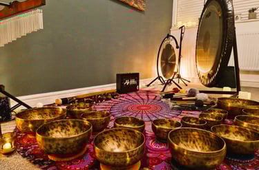 Shruti box, chimes, gongs, and many singing bowls arranged on a mat