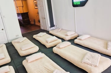 Two rows of four air beds laid on the floor with pillows and blankets