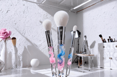 Three makeup brushes with watercolor smoke handles, set in an artist's studio.