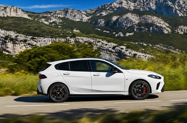 BMW hatch branco em movimento por estrada cercada por montanhas e vegetação