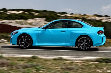 BMW M2 xDrive azul visto de perfil acelerando em estrada com visual esportivo