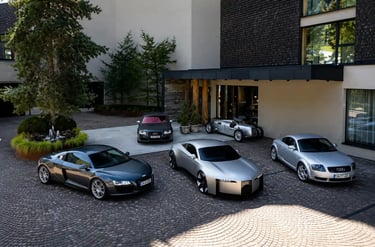 Linha de carros Audi mostra evolução do TT até novo conceito elétrico em pátio moderno.