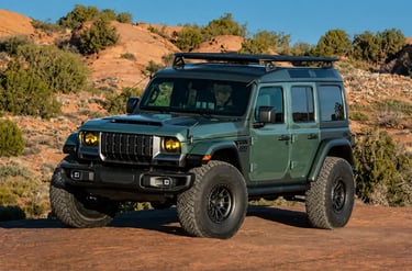 SUV Jeep off-road verde em trilha desértica com pneus para terrenos extremos.