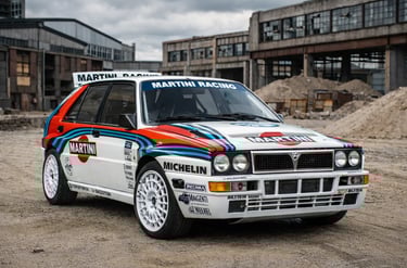carros de rally Lancia Delta Integrale em cenário industrial com terra e galpões ao fundo