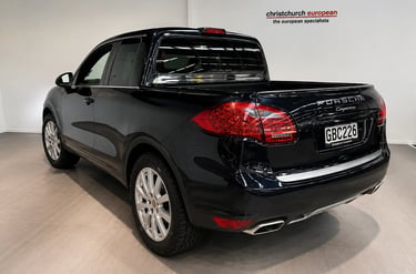 Traseira de Porsche Cayenne transformado em picape de luxo preta em showroom.