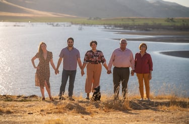 Family portrait photographer in Visalia capturing a group by a lake at sunset.