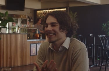 a man sitting at a table with a glass of wine