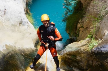 Persona realizando rápel en el barranco de Río Verde, rodeada de formaciones rocosas y agua clara