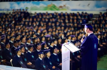 Um homem em uma beca de formatura falando em um microfone