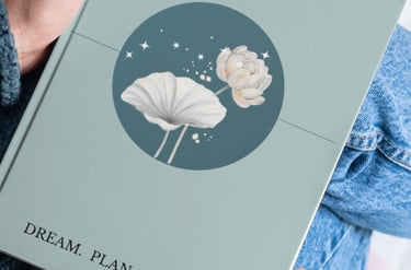 Person holding Mind Your Future daily guided journal with a lotus flower design.