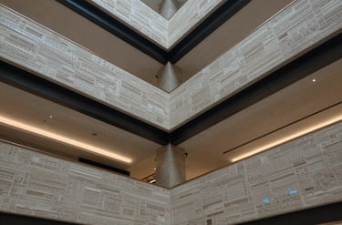 Photo of a modern lobby with complex multi-level drywall ceilings and hidden steel blue lighting. High contrast, architectural detail.