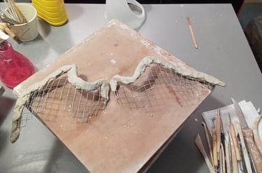 Structure en grillage des ailes de la sculpture Iris partiellement recouvertes d'argile