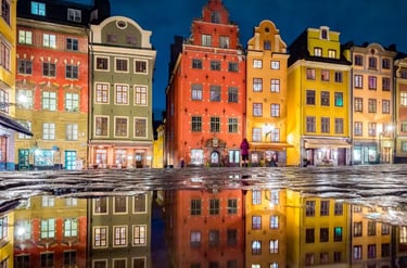 Colorful historic buildings in Stortorget square, Gamla Stan, Stockholm reflected in a rain puddle at night.
