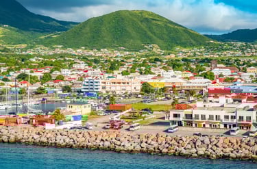 Aerial view of Basseterre harbor in St. Kitts with colorful buildings and a lush green mountain.