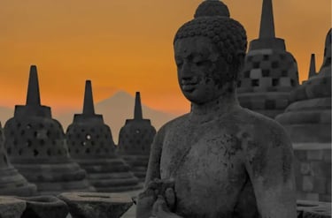 Stone Buddha statue and bell-shaped stupas at Borobudur Temple during a golden sunset in Indonesia.