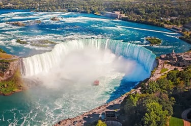 Aerial view of Horseshoe Falls at Niagara Falls with a tour boat navigating the mist-covered river.
