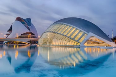 Modern architecture of the City of Arts and Sciences in Valencia reflecting in water at twilight.