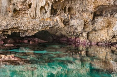 Crystal clear turquoise water reflecting rugged rock formations inside a coastal limestone sea cave.