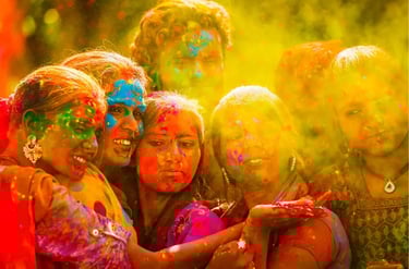 Smiling group of friends celebrating the Holi festival with vibrant yellow and pink powdered colors.